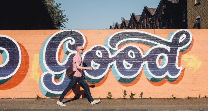 Man walking on heels in front of a wall